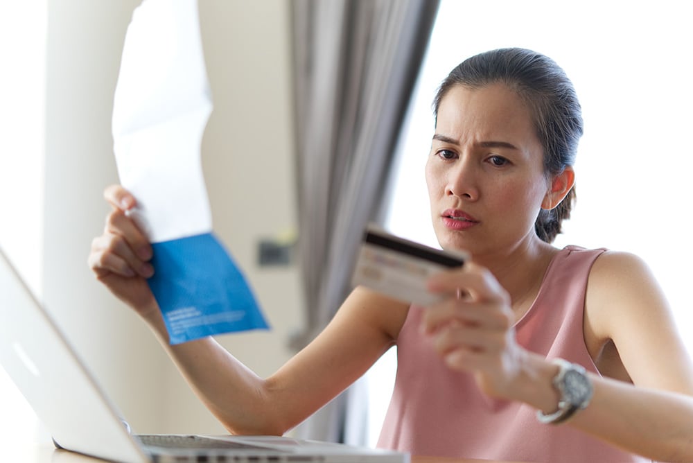 Mujer endeudada sosteniendo una factura de tarjeta de crédito