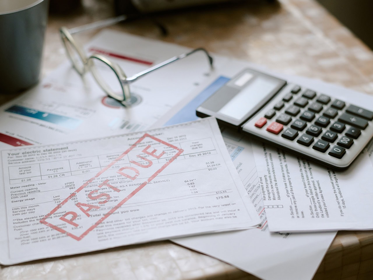 Past due bills and calculator on table